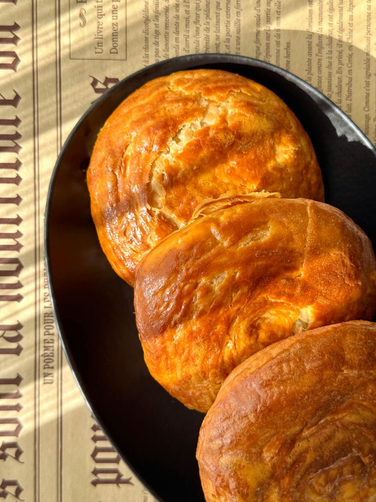 Golden-brown Turkish pastries on a black plate, basking in warm sunlight, creating a cozy ambiance.
